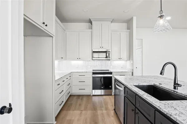 a kitchen with granite countertop a sink stove and cabinets