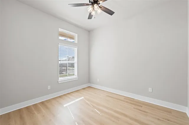 an empty room with a window and a ceiling fan