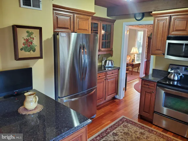 a kitchen with stainless steel appliances granite countertop a refrigerator a stove and a dining table with wooden floor