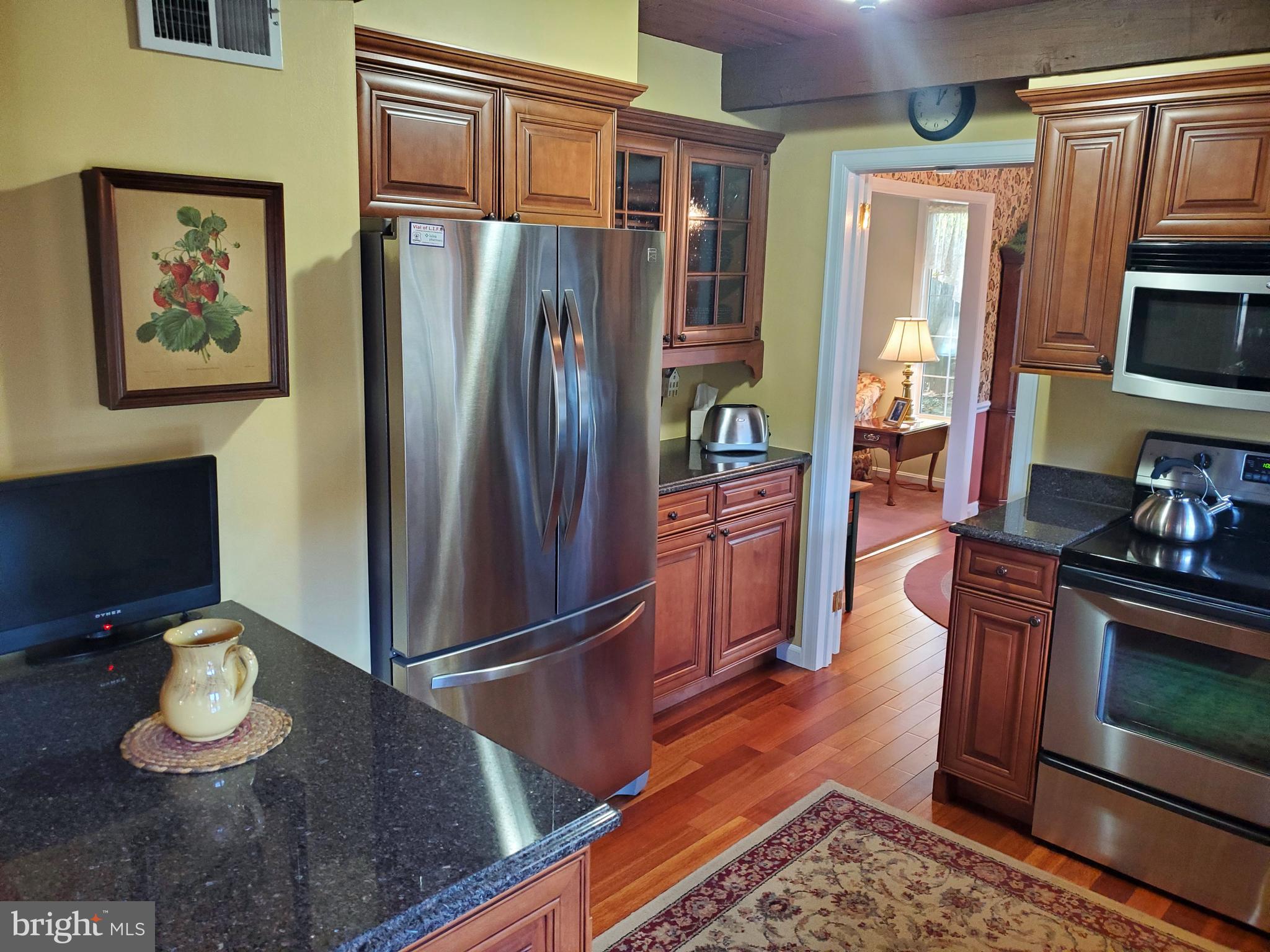 16 Robert Road New Castle, DE 19720 - Photo 12 of 30 a kitchen with stainless steel appliances granite countertop a refrigerator a stove and a dining table with wooden floor