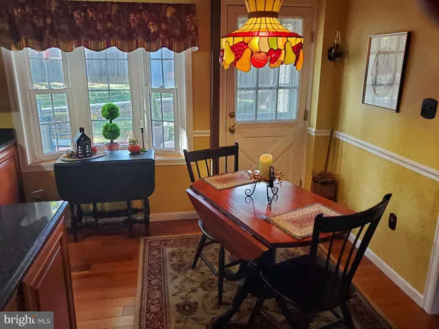 a view of a dining room with furniture a rug and wooden floor