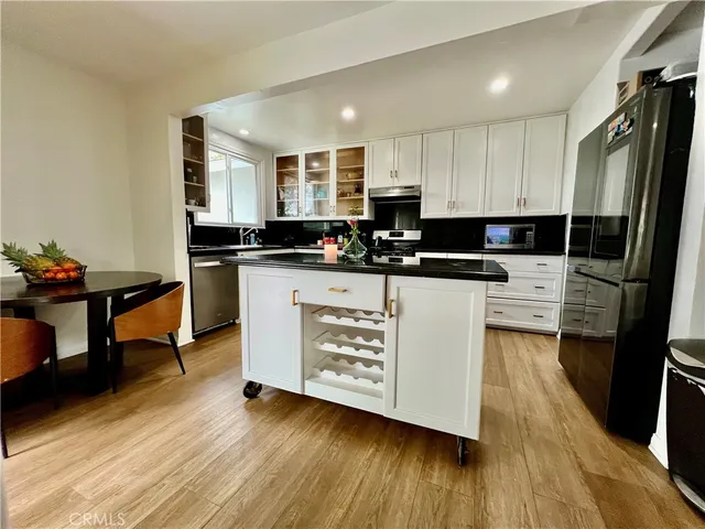 a kitchen with stainless steel appliances a stove a sink a refrigerator white cabinets and wooden floor