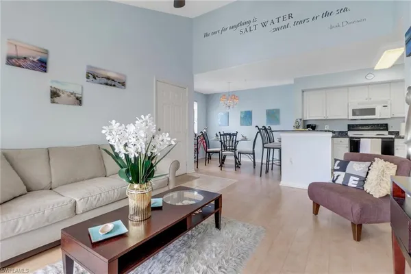 a living room with furniture potted plant and kitchen view