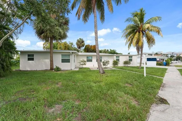 a view of a house with a yard and palm trees
