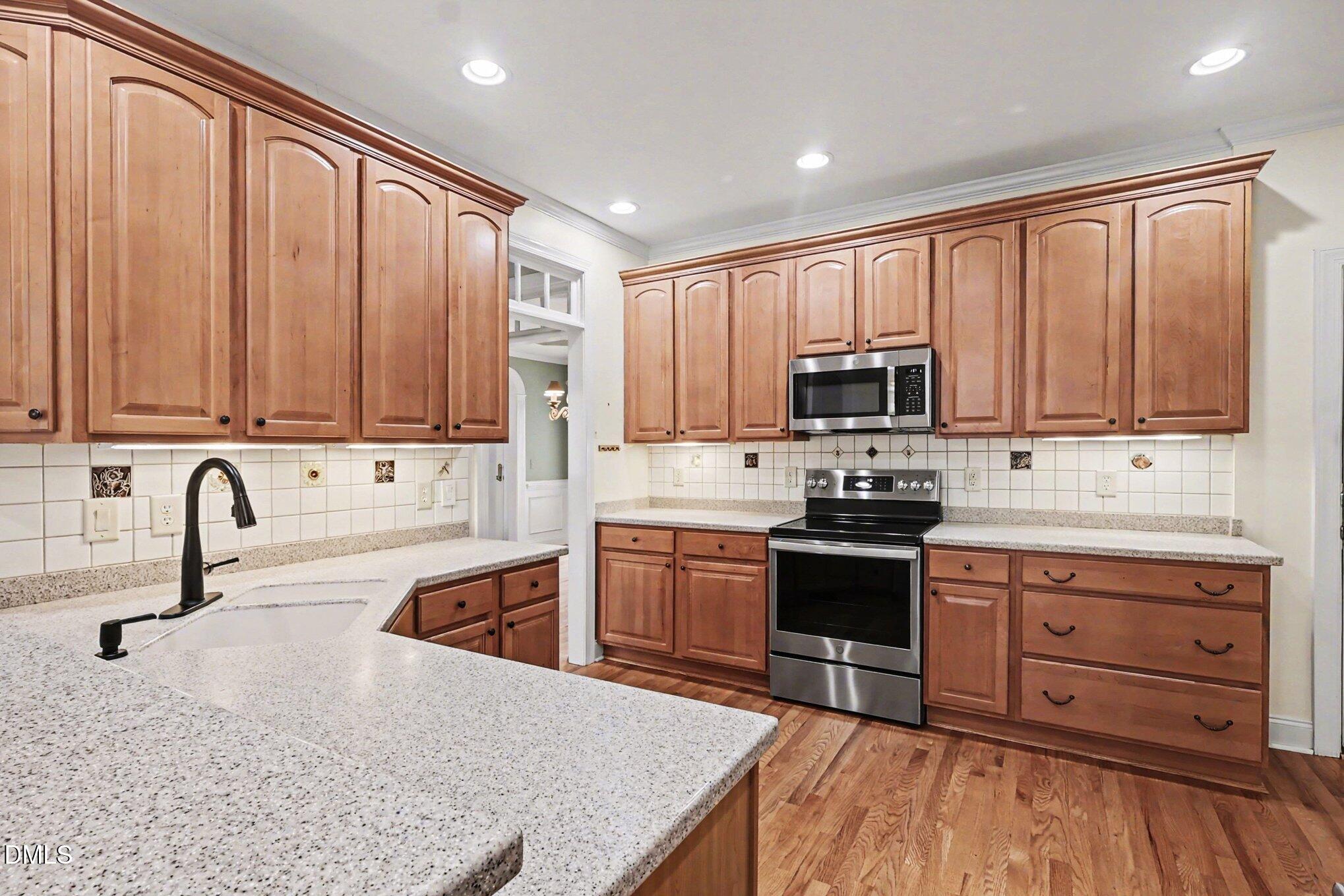 1108 Neuse Ridge Drive Clayton, NC 27527 - Photo 16 of 52 a kitchen with stainless steel appliances granite countertop a sink dishwasher stove and refrigerator with wooden cabinets