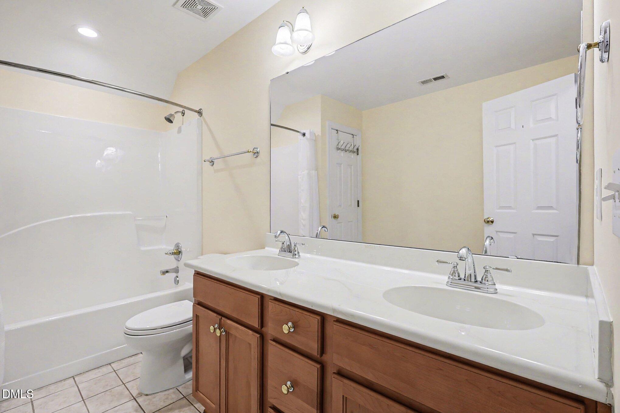 1108 Neuse Ridge Drive Clayton, NC 27527 - Photo 38 of 52 a bathroom with a granite countertop sink toilet a large mirror a shower and a bathtub