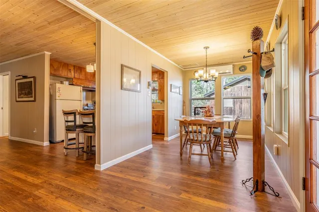 a dining room with wooden floor a chandelier a glass table and chairs