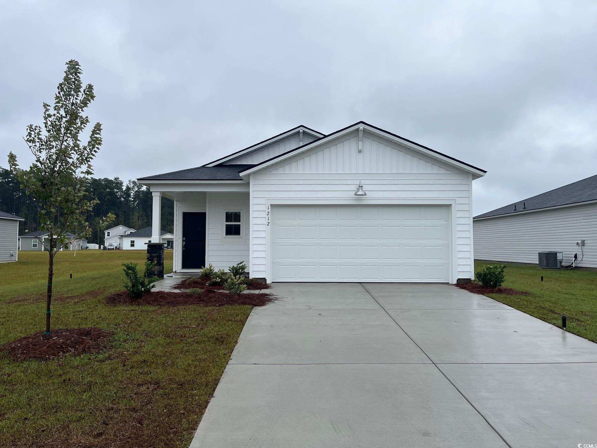 1212 Patchouli Loop Longs, SC 29568 - Photo 1 of 12 Single story home featuring board and batten siding, a front lawn, driveway, an attached garage, and covered porch