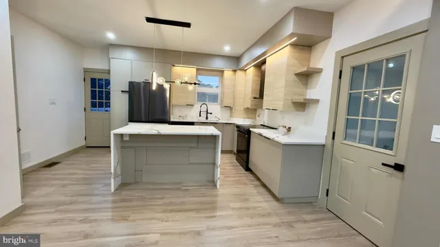 a view of a kitchen with kitchen island stainless steel appliances counter space and wooden floor