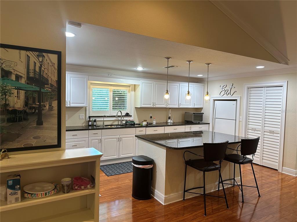 104 Woden Way Winter Haven, FL 33884 - Photo 11 of 48 a kitchen with a stove a refrigerator and a dining table with wooden floor