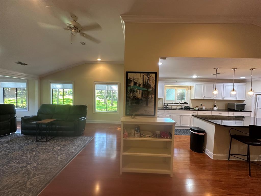 104 Woden Way Winter Haven, FL 33884 - Photo 12 of 48 a open kitchen with granite countertop a refrigerator a stove a dining table and chairs with wooden floor