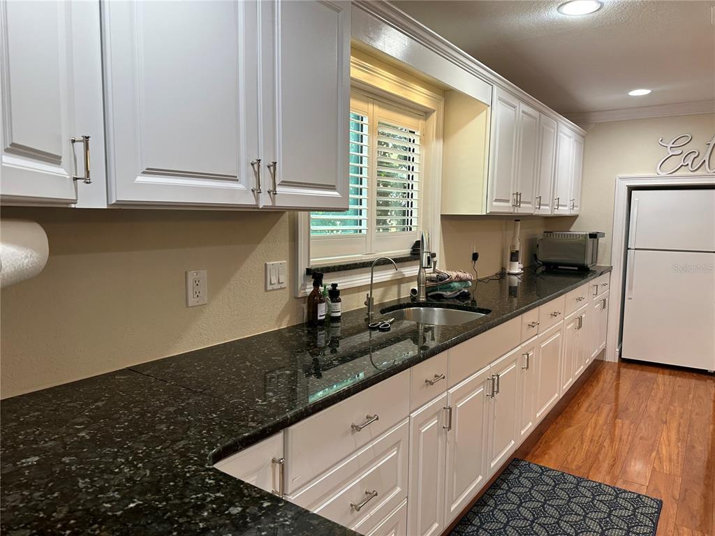 104 Woden Way Winter Haven, FL 33884 - Photo 18 of 48 a kitchen with granite countertop a sink a stove top oven and white cabinets