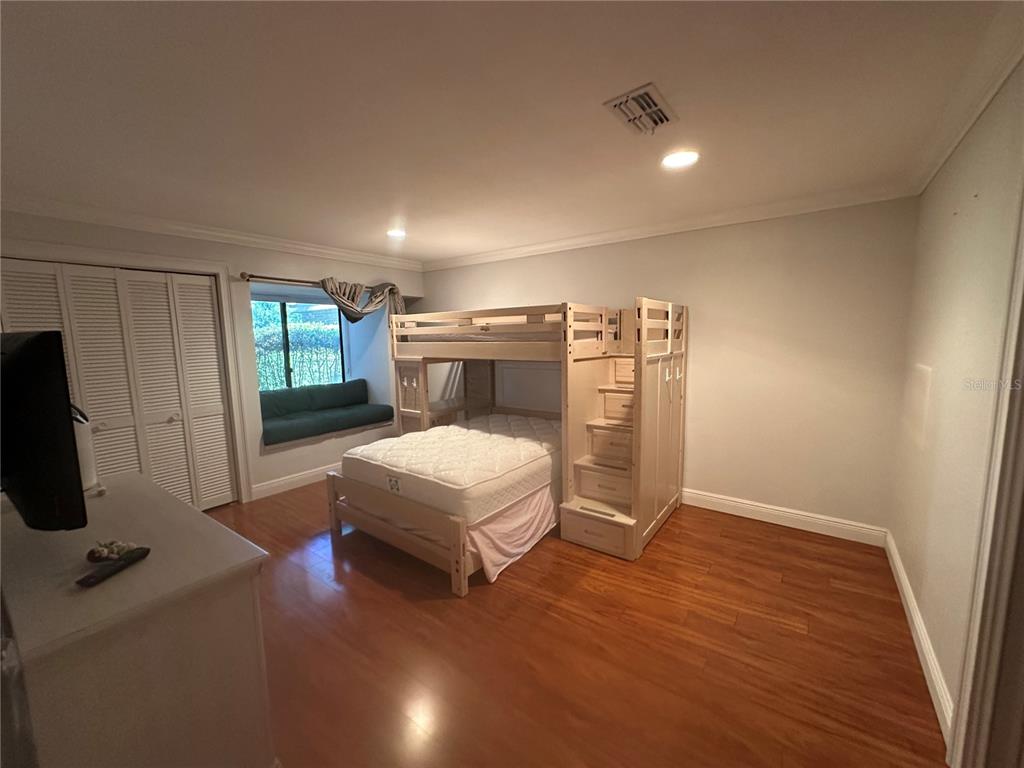 104 Woden Way Winter Haven, FL 33884 - Photo 27 of 48 a bedroom with a bed a mirror on dresser and a wooden floor