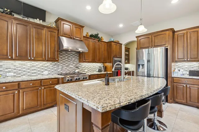a kitchen with granite countertop kitchen island stainless steel appliances a sink stove and refrigerator