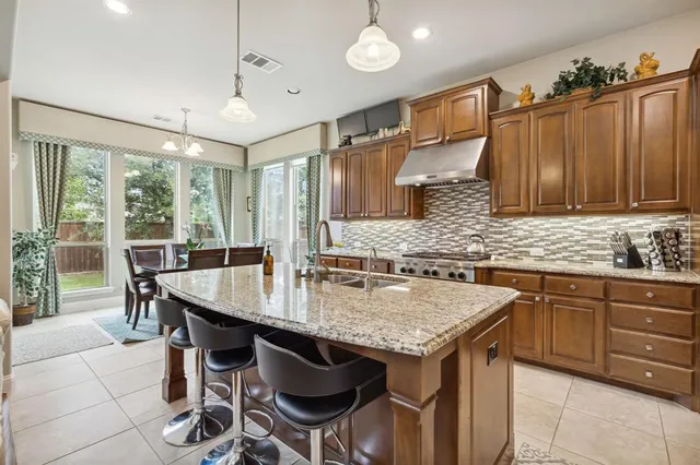 a kitchen with granite countertop a table chairs sink and cabinets