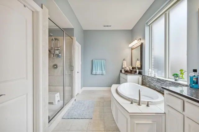 a bathroom with a granite countertop sink a mirror and a bathtub