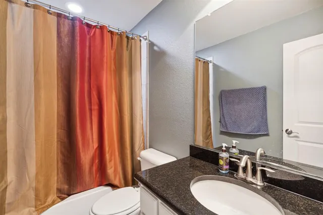 a bathroom with a granite countertop sink and a mirror with toilet
