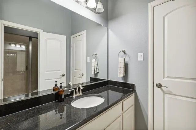 a bathroom with a granite countertop sink and a mirror