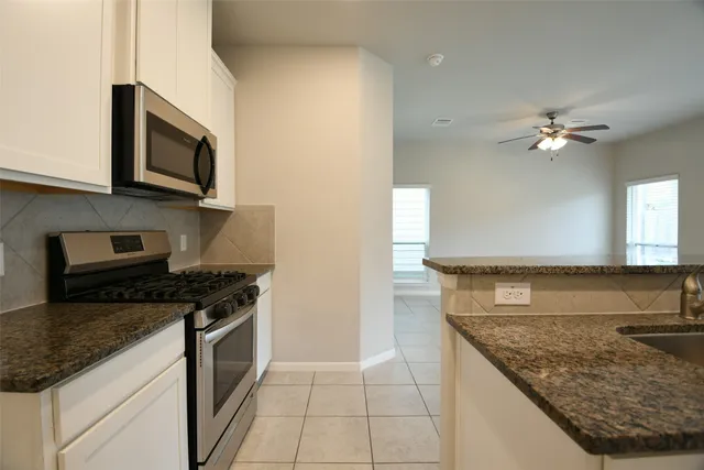 a kitchen with stainless steel appliances granite countertop a sink stove and microwave