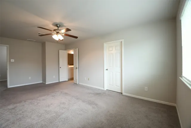 an empty room with chandelier fan and windows