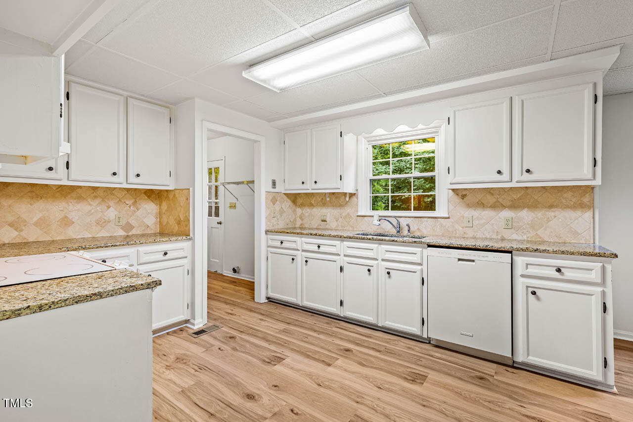 2330 Thunder Road Durham, NC 27712 - Photo 10 of 44 a kitchen with granite countertop white cabinets white appliances a sink and a window