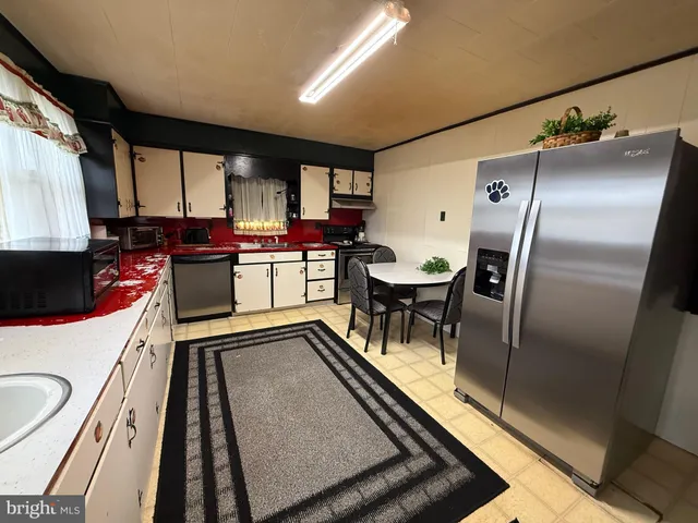 a kitchen with stainless steel appliances granite countertop sink stove refrigerator and cabinets