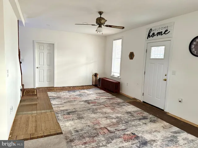 a view of a livingroom with wooden floor and a ceiling fan