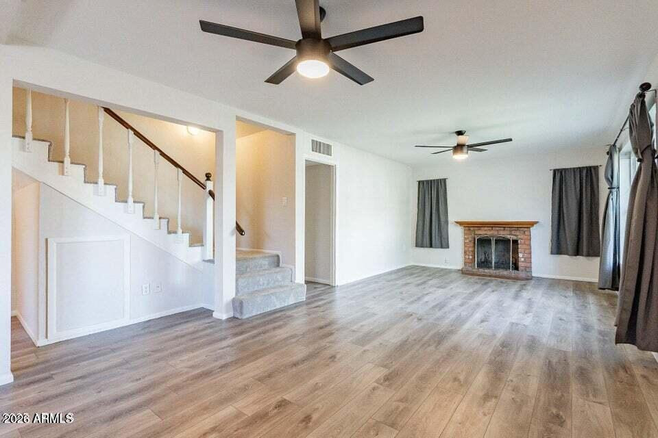 505 West Howe Street Tempe, AZ 85281 - Photo 4 of 20 a view of an empty room with wooden floor a ceiling fan and a fireplace