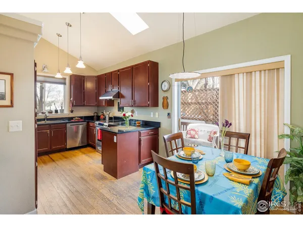a kitchen with stainless steel appliances kitchen island granite countertop a table chairs and a living room