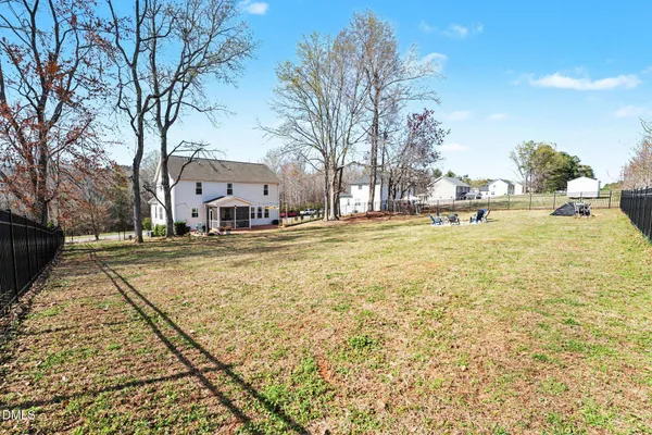 a view of a yard with yellow house in the background