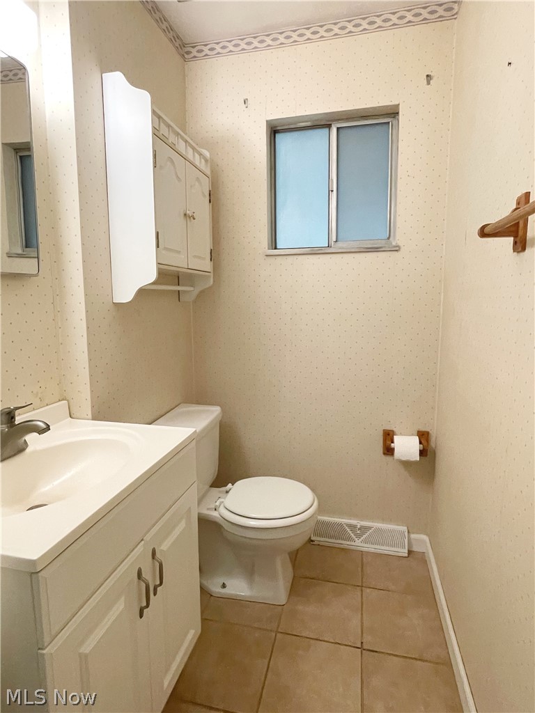 686 Shook Road Akron, OH 44319 - Photo 13 of 22 Half bath on the main level, with vanity, coordinating wall-mounted storage cabinet, and tiled flooring.