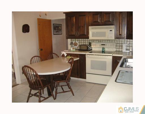 856 Ridge Road Monmouth Junction, NJ 08852 - Photo 2 of 7 a kitchen with stainless steel appliances a stove a sink a microwave a dining table and chairs