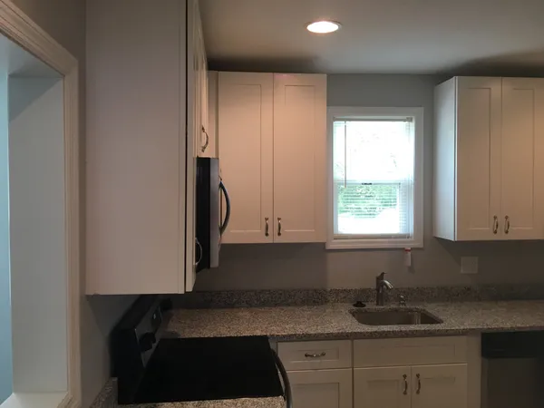 a kitchen with granite countertop white cabinets and window