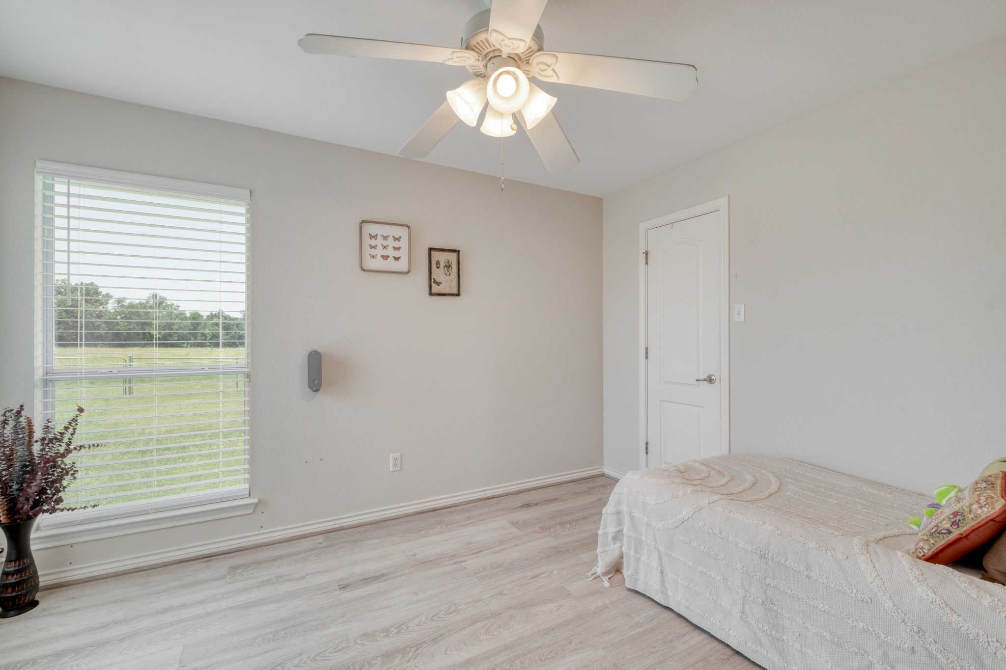 341 Brown Road McDade, TX 78650 - Photo 25 of 38 A quiet bedroom with light wood flooring, offering serene views through a large window.