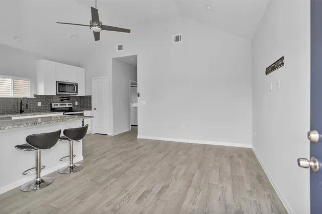 a kitchen with granite countertop a table chairs refrigerator and microwave