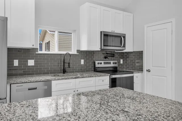 a kitchen with stainless steel appliances granite countertop a sink stove and microwave