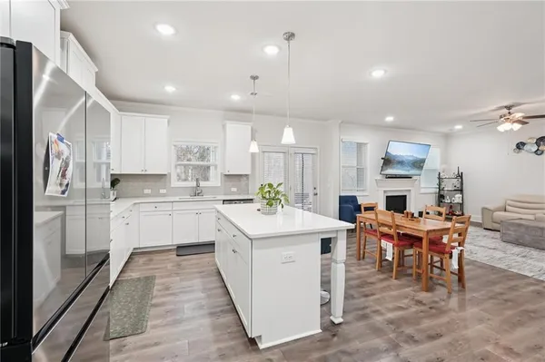 a kitchen with stainless steel appliances granite countertop a sink a stove a refrigerator and white cabinets with wooden floor