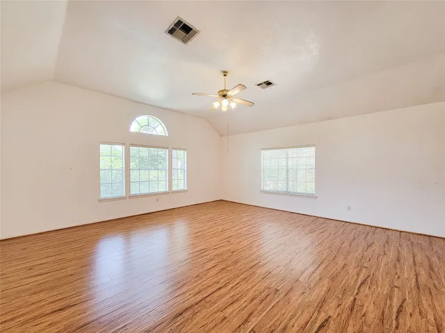 an empty room with wooden floor and windows