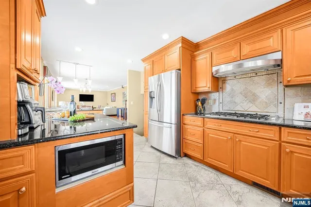 a kitchen with stainless steel appliances granite countertop a refrigerator a stove and a sink