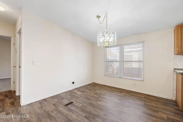 an empty room with wooden floor chandelier and windows