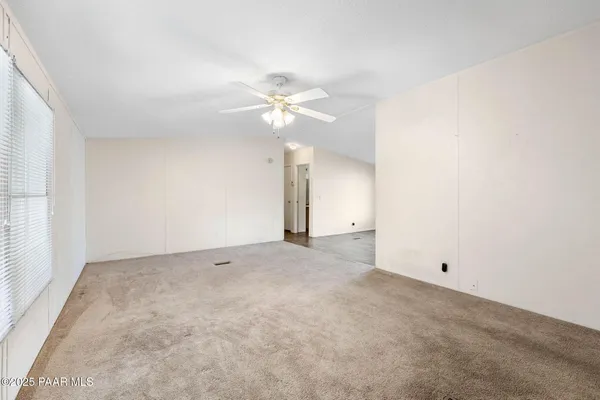 an empty room with a chandelier fan and closet
