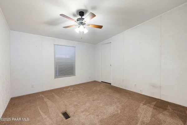an empty room with a chandelier fan and windows