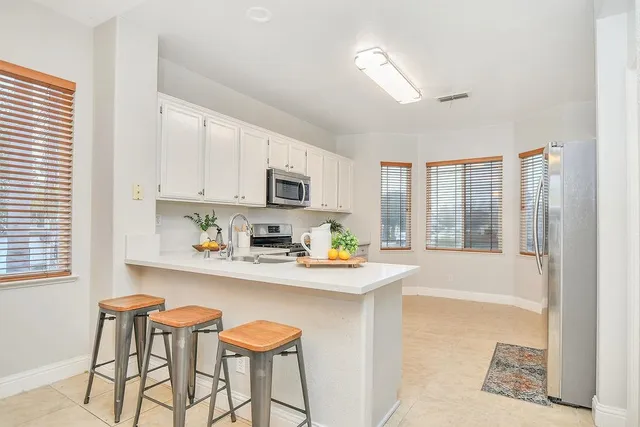 a kitchen with stainless steel appliances granite countertop white cabinets a stove a sink and a microwave