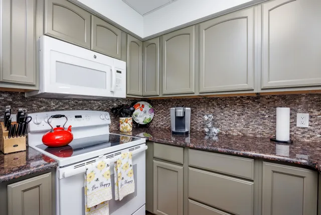 a kitchen with granite countertop a sink a stove and cabinets