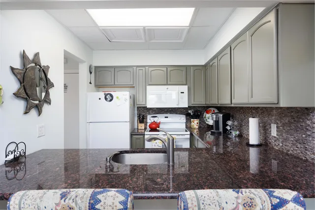 a kitchen with granite countertop a sink and a stove top oven