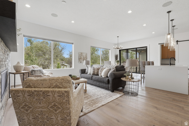 653 East Vandalay Lane Draper, UT 84020 - Photo 10 of 61 Bright living area featuring large windows, wood-finish flooring, recessed lighting, and a stone-clad fireplace