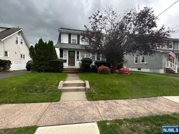 a front view of a house with a garden and trees