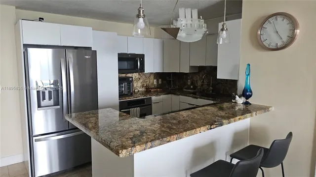 a kitchen with granite countertop white cabinets and stainless steel appliances