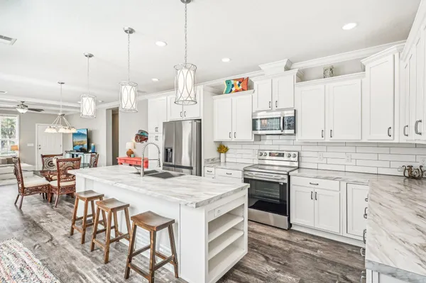 a kitchen with stainless steel appliances kitchen island granite countertop a stove a sink and a refrigerator