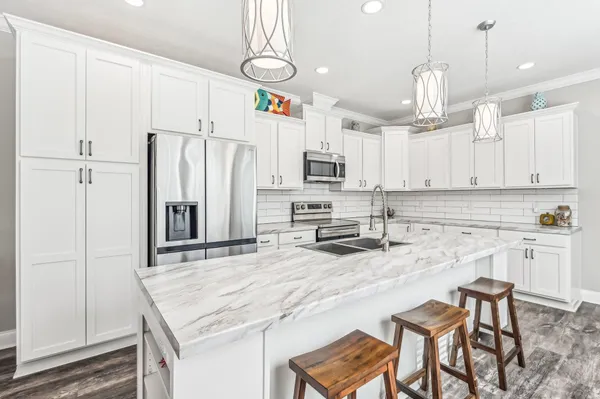a kitchen with kitchen island granite countertop a white cabinets and refrigerator with wooden floor